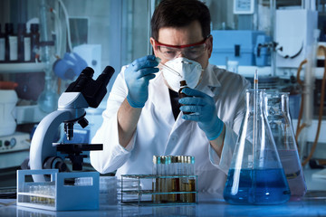 researcher working in the laboratory dropping samples of liquid reagent in a test tube / scientist...