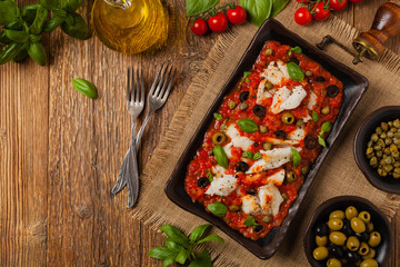 Fototapeta na wymiar Cod in Italian in tomatoes with olives and capers.