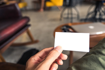Closeup image of a man's hand holding empty business card in cafe