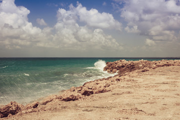 Fototapeta na wymiar summer southern view of the sea shore. the wave runs on the rocks. vintage vanilla tinted