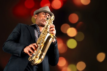 Fototapeta na wymiar Close-up man playing on saxophone on blurred background