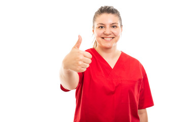 Young medical nurse wearing red scrub showing thumb up gesture.