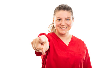 Young medical nurse wearing red scrub pointing finger to camera.