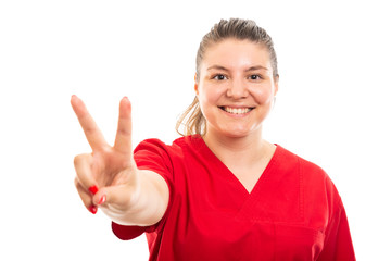 Young medical nurse wearing red scrub showing peace sign.