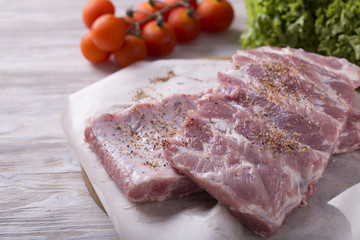 Raw ribs with  vegetables on crumpled paper.