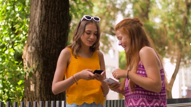 technology, leisure and people concept - happy smiling teenage girls with smartphones in summer park