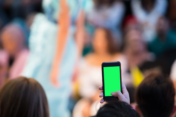 Front row VIP guests people from audience filming vdo fashion show with mobile smart phone