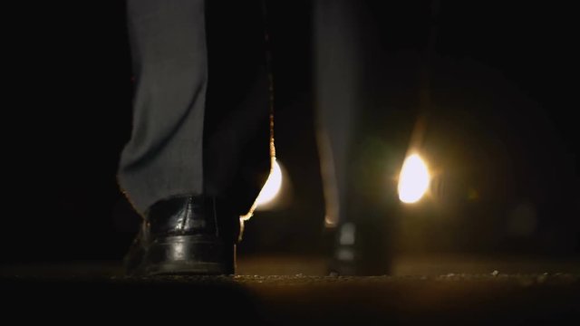 Man approaching to car with headlights on, night negotiations with bandits