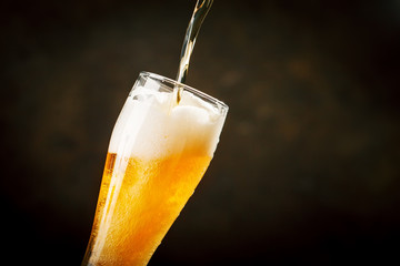 A glass of beer on a dark background.