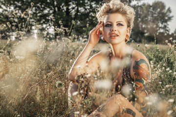 Fototapeta na wymiar Sharp looking blonde. Summertime female portrait. Young adult woman with tattos. 11 August 2018, Kiev, Ukraine
