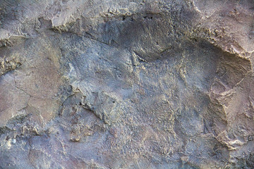 Texture of a multi-colored wall with plaster, cracks, rubs, stains and granularity.