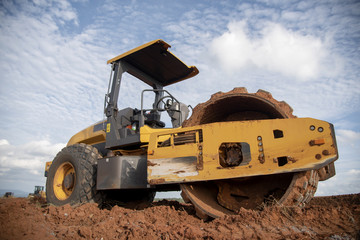 Yellow vibratory soil compactor working on highway construction site