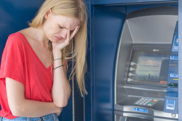Fototapeta na wymiar Sad woman standing in front of a ATM bank machine. No money.