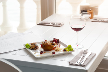 dinner or lunch with dish per one person. luxury white interior of restaurant. red wine and chicken with pear