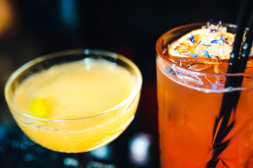 two cocktails at bar counter. orange red and yellow drinks