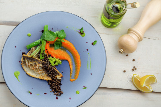 Seabass fish fillet stake cooked on a grill with healthy vegetables on a plate. Healthy seafood food on a   rustic wooden table. Directly above top view shot.