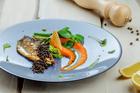 Delicious grilled seabass fish fillet steak with vegetables. Healthy meal made of seafood fish and vegetables on a table. Close-up shot.