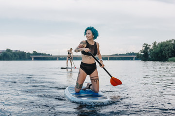 sportive women standup paddleboarding on river