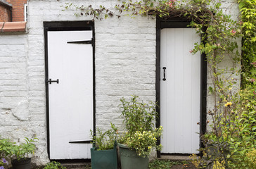 An old brick built shed with two black and white painted doors