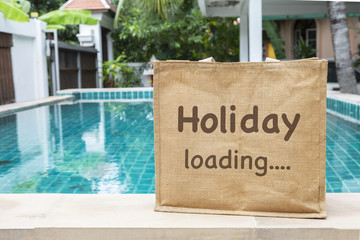 Holiday loading eco bag over blurred swimming pool and garden background