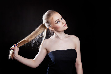 Naklejka premium Beauty fashion model girl with long healthy smooth straight hair ponytail hairstyle on black background. Smiling pretty woman looking camera. Perfect Fresh Skin Portrait. Youth and Skin Care Concept