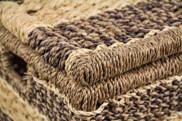Closeup of icker storage basket with hinged lid, covered container, made of natural bamboo, isolated on white background, shallow depth of field