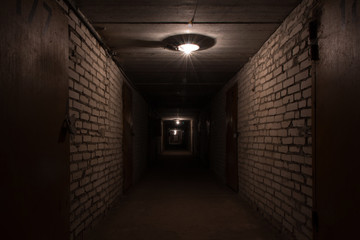 Dark long corridor in a basement with metal doors