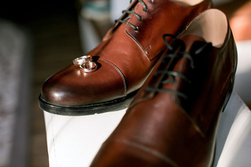 Man groom in a wedding suit at a window with flowers and wedding accessories
