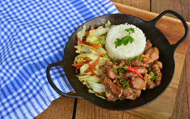 Fried sliced pork with garlic and pepper  served with Fried vegetable and Thai rice in small wok.