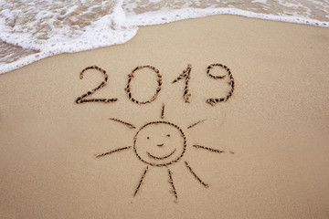 Year 2019 written at the caribbean sand beach with sea wave .