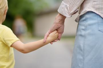 Beautiful granny and her little grandson walking together in park
