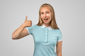 Studio portrait of happy cute young successful woman giving thumbs up gesture in full disbelief isolated on white wall background. Positive human emotion, facial expression, body language concept
