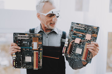 Standing Old Worker with Motherboards in Hands.