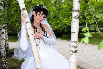 The bride in a wedding dress is at the birch.