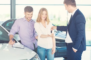 Obraz premium Happy couple with car dealer