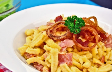 Spätzel or Spaetzel or soft egg noodle fried with ham ,cheese and Topped with fried onions and bacon.