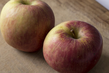 Fototapeta na wymiar Two red autumn apples fruit on a wooden table