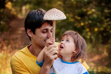 Dad with his daughter in woods, rejoice at the found edible mushroomю Autumn Mushroom Picking Season