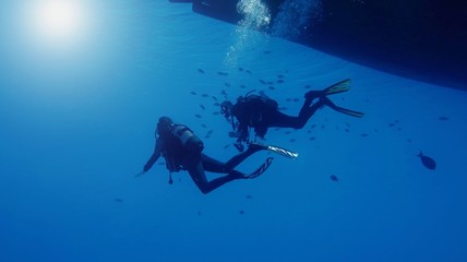 Obraz na płótnie Canvas Couple of scuba divers descending from the boat into the depth
