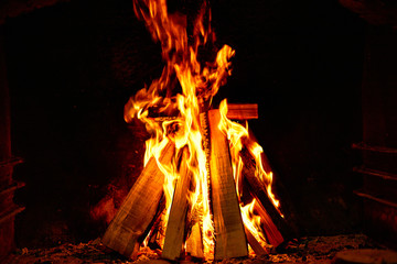Burning firewood in the fireplace on a dark background.