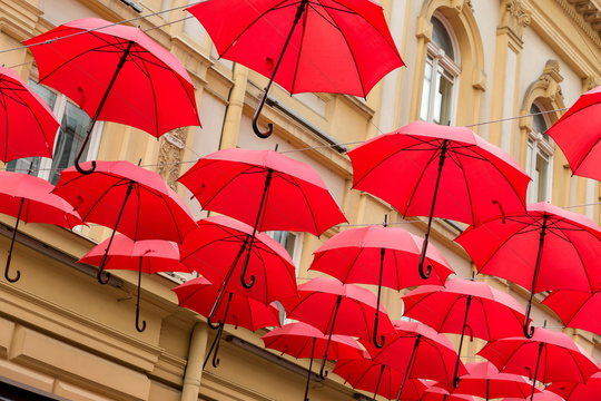 Many red umbrellas hanging in the city street with the yellow building in background Belgrade, Serbia