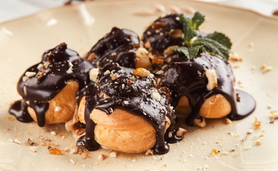 French profitroles with chocolate icing and mint leaves