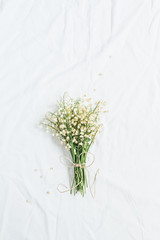 Lily of the valley flowers bouquet on white background. Flat lay, top view minimal floral concept.