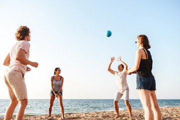 Friends outdoors on the beach play volleyball having fun.