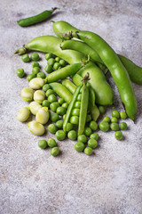 Fresh green peas and beans on light background