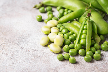 Fresh green peas and beans on light background