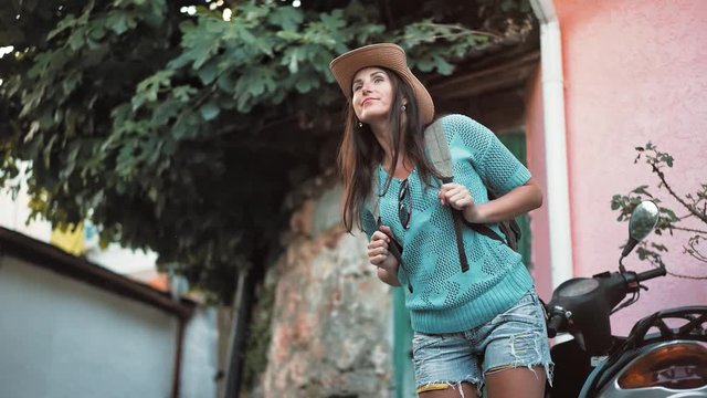 Low angle attractive hipster backpacker female in hat worried looking around waiting for somebody