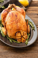 Whole roasted chicken with lemon and rosemary on a black plate. Rustic style. Christmas concept. Christmas turkey. Top view.