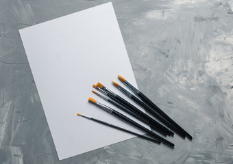 Painting brusches, white paper on gray concrete background