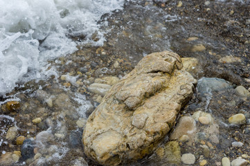 pebble stones on the sea beach, the rolling waves of the sea with foam